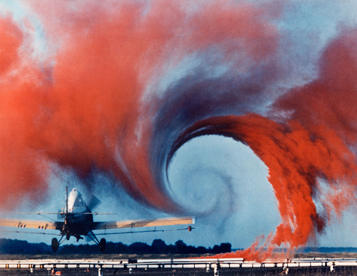 Wingtip vortex behind a plane visualised with red smoke.